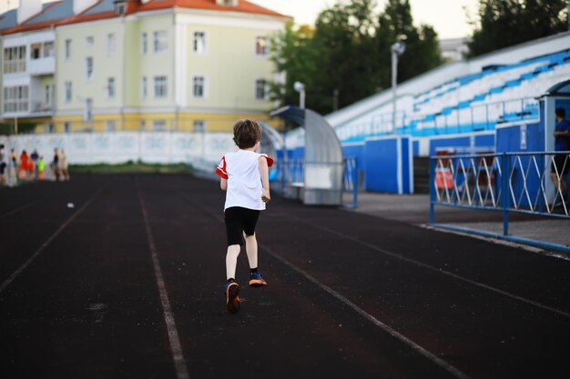 그 아이는 경기장에서 스포츠를 하러 간다 소년은 축구를 하기 전에 훈련하고 있다