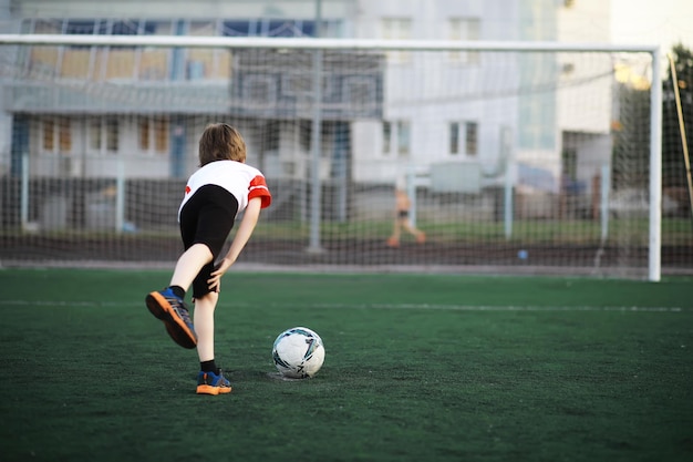 The child goes in for sports at the stadium The boy is training before playing football