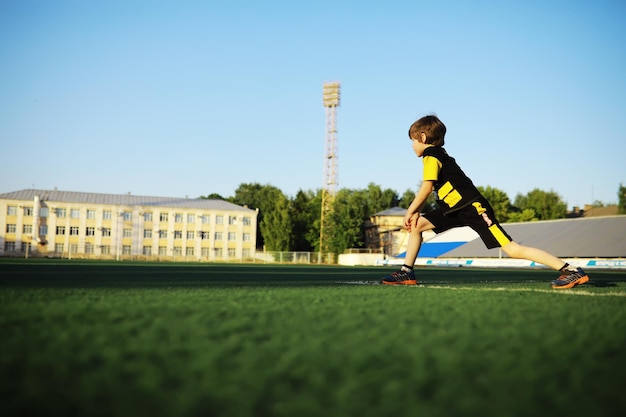 子供はスタジアムでスポーツに行きます男の子はサッカーをする前にトレーニングしています