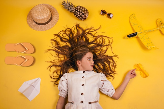 Photo the child goes on a trip, a young girl lies on a yellow background