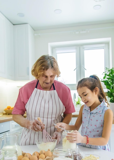 Child and grandmother in the kitchen bakes prepares the dough in the kitchen Selective focus