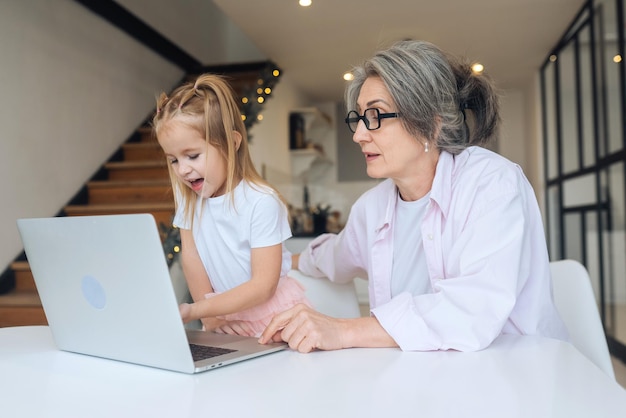 Child and granny looking at the camera with laptop