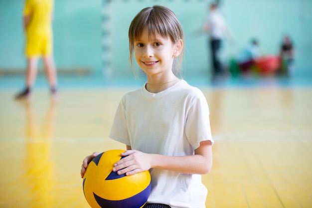 Ребенок в спортзале Школьница с мячом на уроке физкультуры