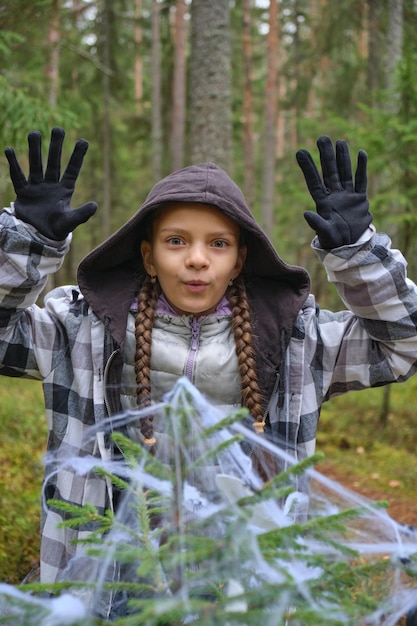 Un bambino in costume di halloween fa le facce che una ragazza si nasconde dietro un albero decorato per halloween