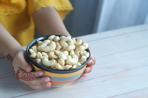 Child hand hold bowl of cashew nut