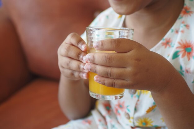 child hand holding a glass of orange juice