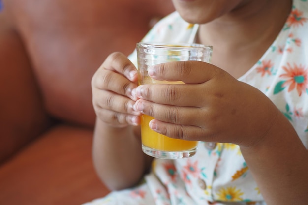 Child hand holding a glass of orange juice