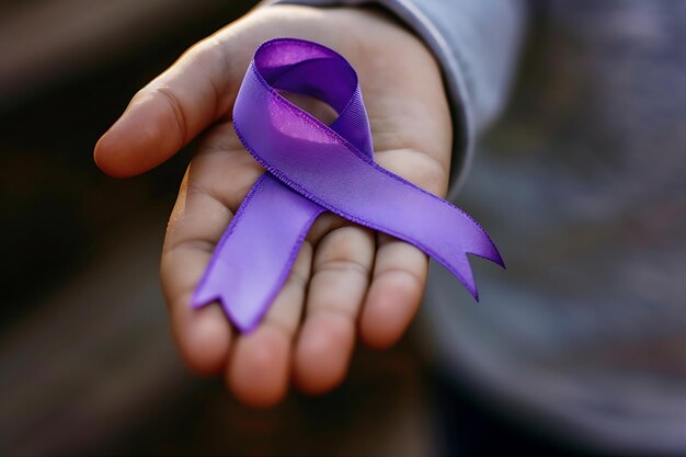 Photo child hand holding purple cancer ribbon in the sun