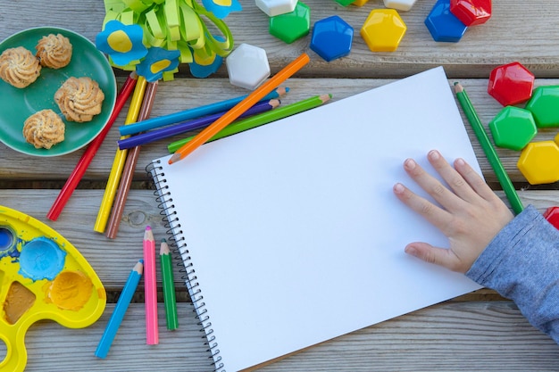 Child hand with empty white paper list mockup drawing tools