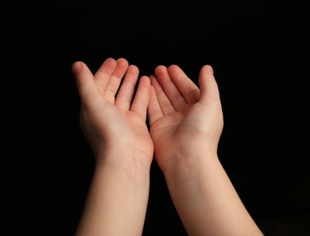 Child hands on black background