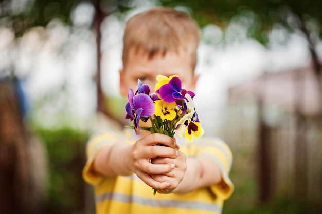 花束パンジーの花を持つ子供の手。花に焦点を当てる