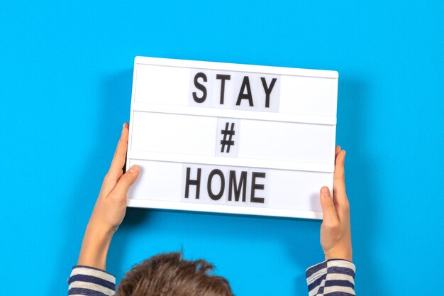 Child hands holding light box with text stay home