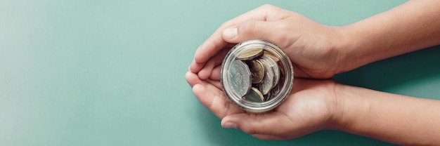 Child hands holding money jar, donation, saving, charity, family finance plan concept