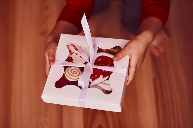 Child hands holds gift box with cookies Crafting decoration festive gingerbread cookies