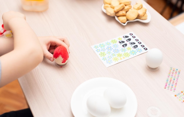 Child hands painting easter eggs selective focus Happy Easter concept Process of crafting at home Greeting card with copy space