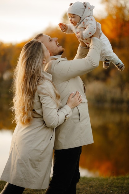 The child in the hands of the parents. Happy family walk in autumn in the park.