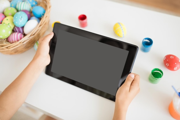 child hands with tablet pc easter eggs and colors