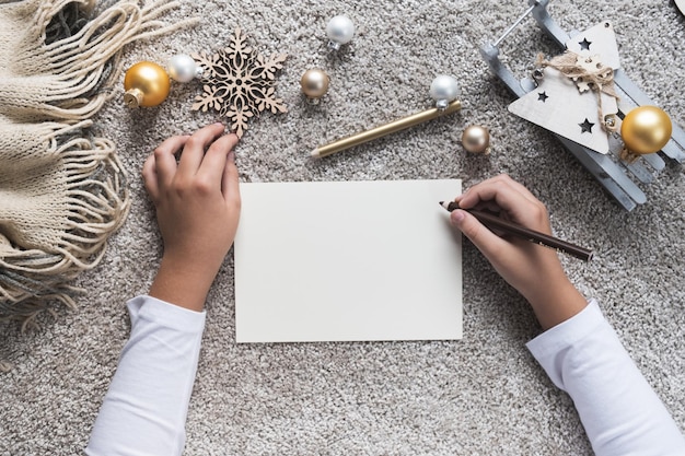 Child hands writes letter on empty sheet of paper Christmas and New year concept