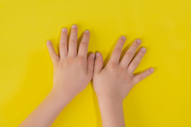 Foto mani del bambino sulla superficie gialla