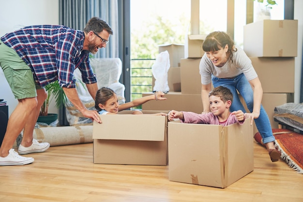 Child happiness and boxes with family moving in apartment for fun and enjoyment on the floor Parents happy and children excited in a box at family home for investment and a lifestyle with love