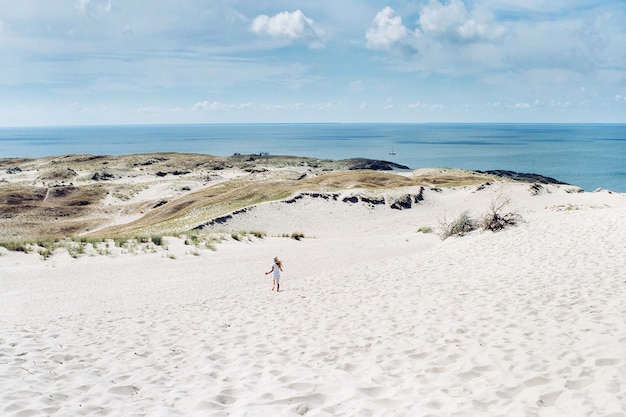 A child has fun in the sand dunes on the beach in Nida.