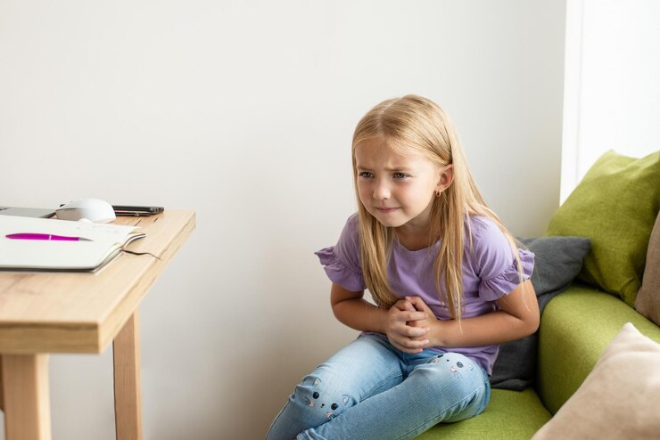The child has a stomach ache, he holds his hands where he feels pain, the health of modern children