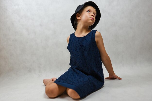 Child in a hat and blue dress posing in the studio