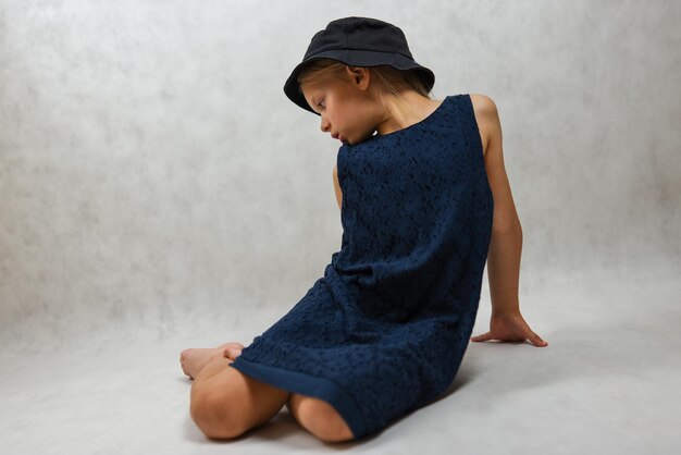 Child in a hat and blue dress posing in the studio