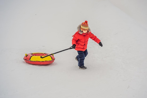 写真 子供がスノーチューブで楽しんでいる少年がチューブに乗っている子供のための冬の楽しみ