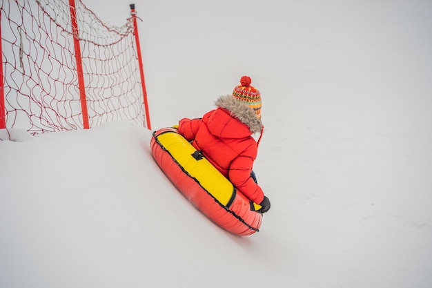 스노우 튜브에서 즐거운 시간을 보내는 아이 튜브를 타고 있는 소년 아이들을 위한 겨울의 즐거움