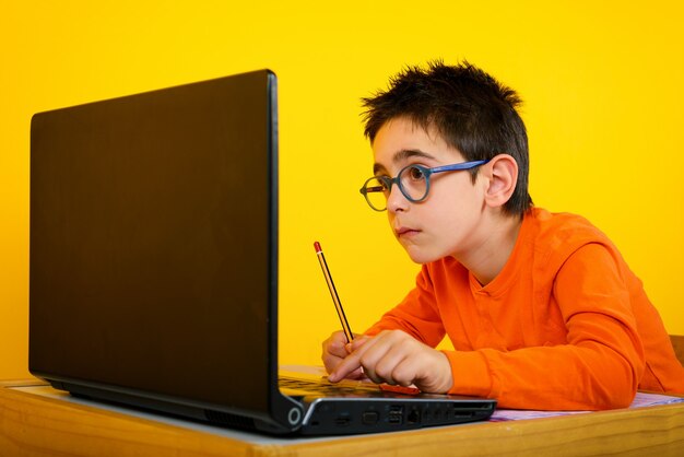 Child hears a remote lesson with the school teacher due to covid-19 pandemic on yellow