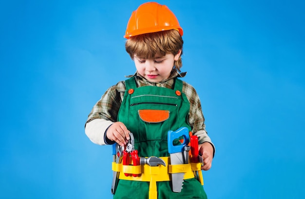 Child in helmet and in builder uniform with tool belt kid boy repairman with tools for building