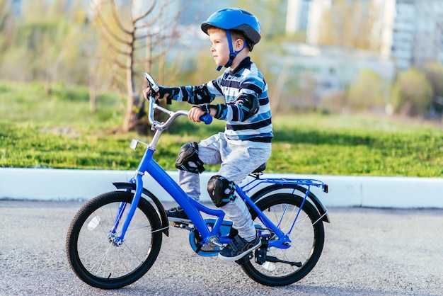 A child in a helmet and protection in a bike ride on nature in the spring