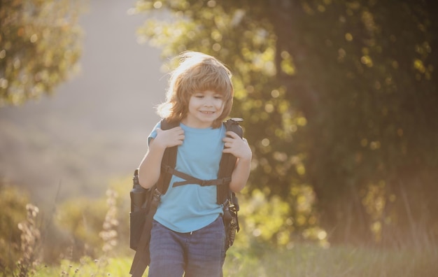 Child hiker with backpack hike in hills background Cute boy with hiking equipment in the mountains