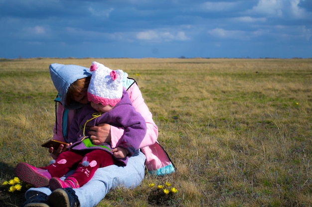 A child and his mother are sitting on the lawn spring cool weather