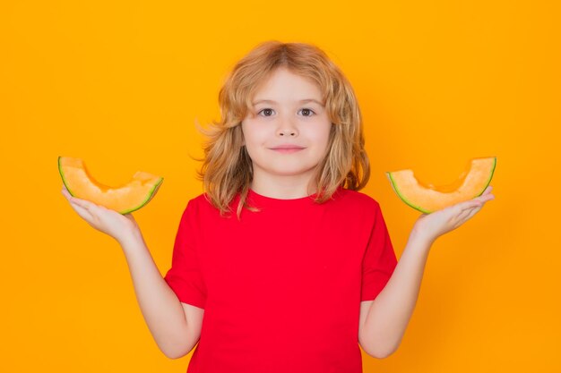 Child hold red melon in studio Melon fruit Studio portrait of cute kid boy with melon isolated on yellow
