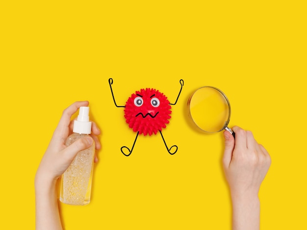 Child holding antiseptik spray and see cartoon Covid-19 bacteria on table through a magnifying glass.