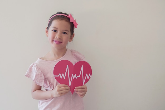 Foto bambino che tiene grande cuore rosso con cardiogramma