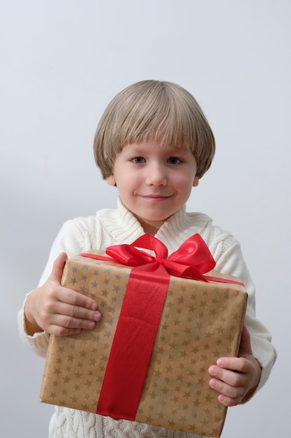 Foto contenitore di regalo di natale della holding del bambino in mano. ragazzo isolato su sfondo bianco. anno nuovo e concetto di natale.