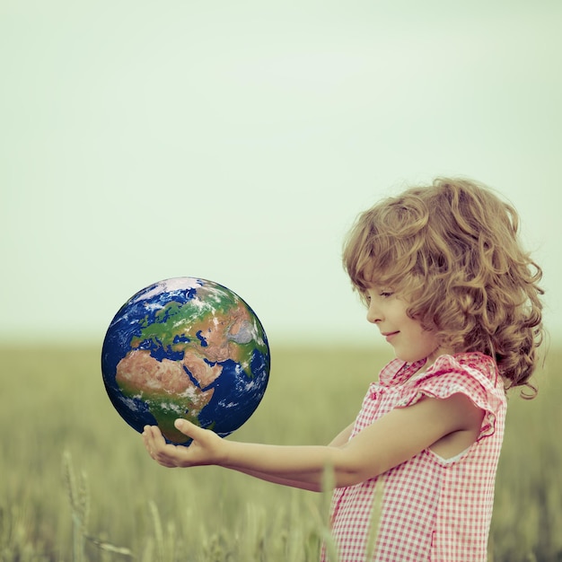 NASA에서 제공한 이 이미지의 녹색 봄 배경 요소에 지구를 손에 들고 있는 아이