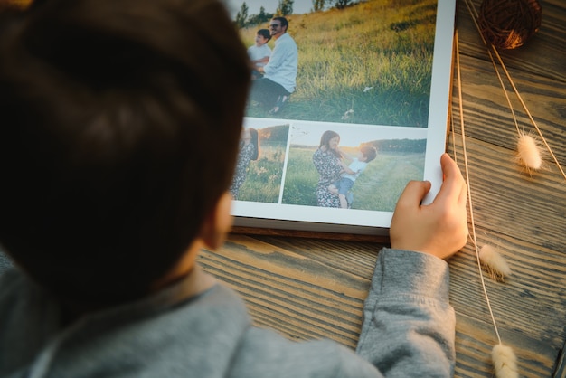 木製のテーブルに家族の写真アルバムを保持している子供