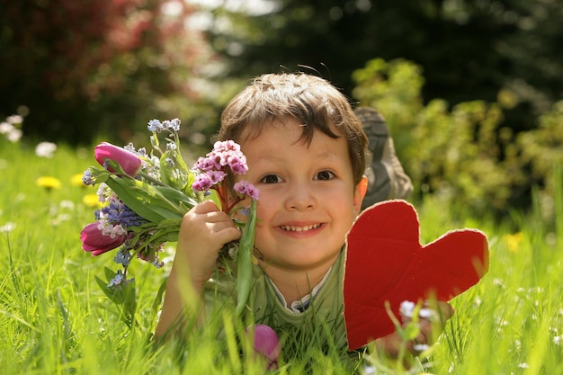 Photo a child holding a heart and a bunch of flowers