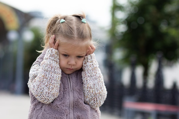 Child holding her head by hands feeling stress