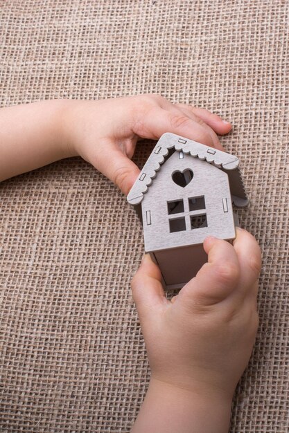 Child holding a model house on a canvas