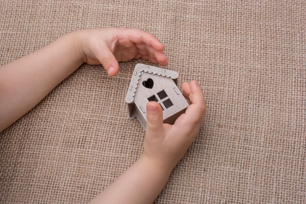 Child holding a model house on a linen canvas