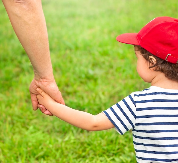 Child holding parents hand outdoors