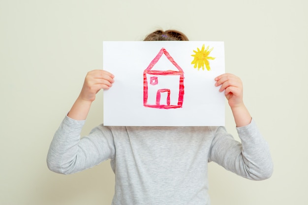 Child holding picture of house.