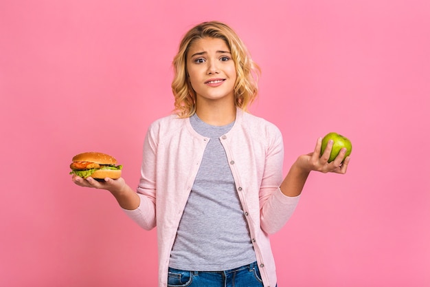 Child holding a piece of hamburger and green apple