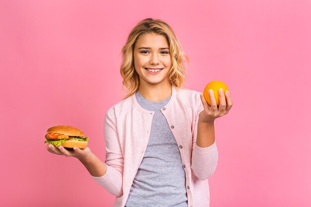 Child holding a piece of hamburger and orange