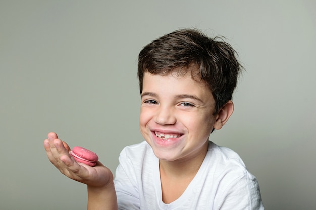 child holding a pink macaroon